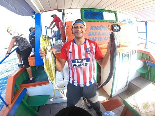 pescador segurando dois grandes peixes