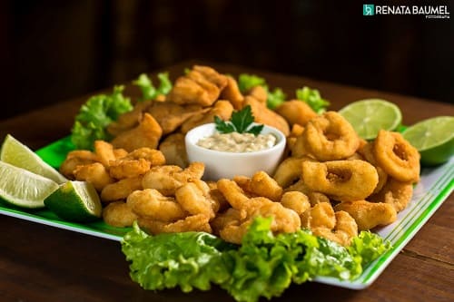 foto de uma porção de camarões fritos empanados com um molhinho no centro