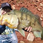 garoto pescador mostrando um belo tucunaré que pegou