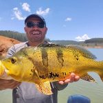 pescador mostrando um tucunaré amarelo