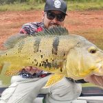 pescador feliz segurando seu tucunaré amarelo