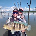 dois pescadores segurando um tucunaré azul grande