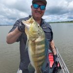 pescador mostrando um tucunaré azul