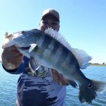 pescador posando para a foto com um tucunaré azul